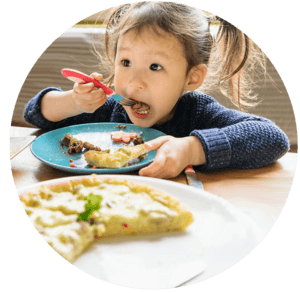 huge cropped image of a young girl with ponnies, eating her omelet food on the table
