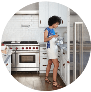 huge cropped image of a woman puttin a kettle on a stove in her kitchen