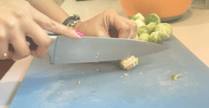 image of woman's hands slicing brussels on a chopping board